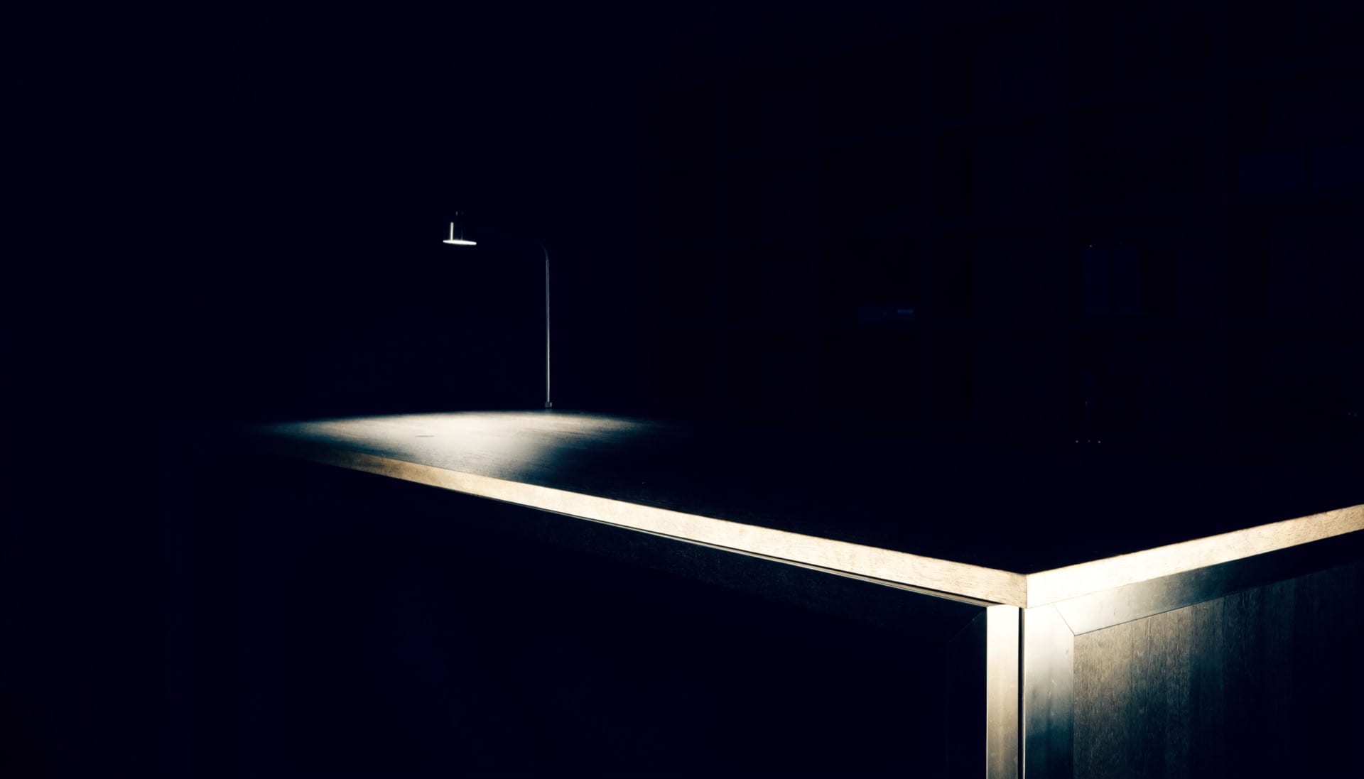 Der dunkle Verkaufstresen des Ladenlokals, abends, unter einer einzelnen Lampe.
