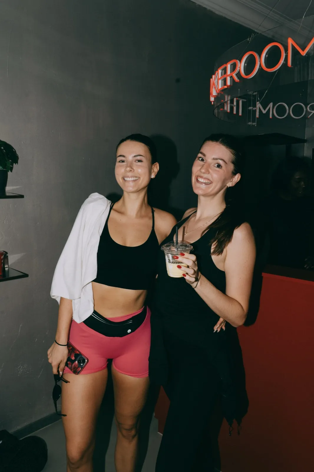 Two guests at the Shakeroom neon sign